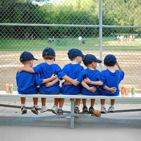 Kids baseball team on bench with juice bottles